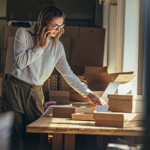 vendedora atendiendo llamadas y revisando cajas de productos